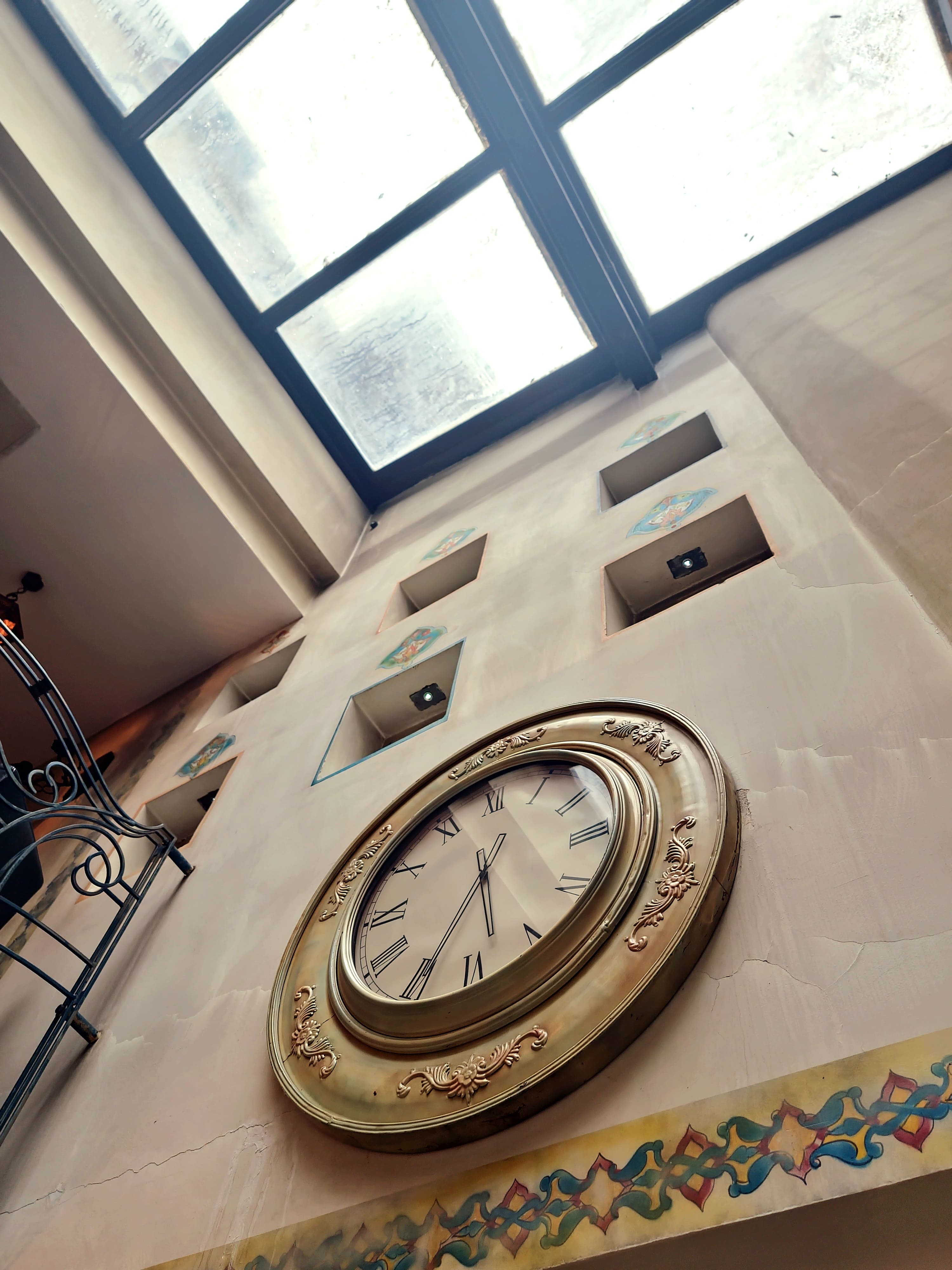 Brass clock on tadelakt wall with arabesque windows